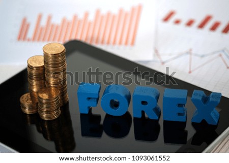 FOREX text and stack of coin with tablet computer and financial graph chart on paper, business planning vision and finance analysis concept idea.