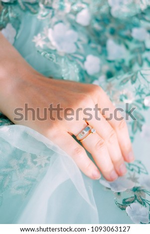 Tender feminine hand with engagement and marriage rings holding mint fabric dress