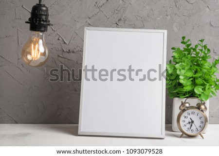 Empty frame on the background of a wall with a flower and an Edison bulb. Concept inscriptions for text, advertising, fonts