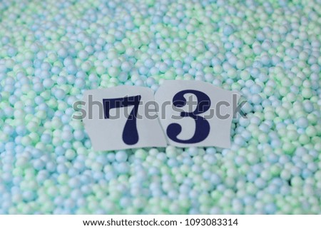 The number 73 of the piece of paper in a pile of small spheres