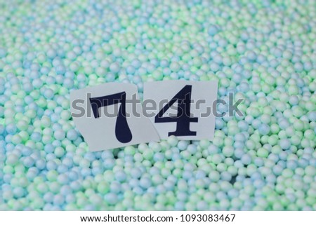 The number 74 of the piece of paper in a pile of small spheres