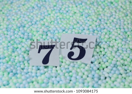 The number 75 of the piece of paper in a pile of small spheres