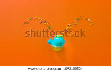Jelly shape Blue whale spray colored Rainbow Sprinkles.Top view on orange background creative concept.