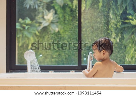 Bath time, rear side of adorable little boy bathing in bathtub with warm water from shower. Rear side of Asian toddler take a bath in bathtub by himself. Concept for learn about daily routine. Royalty-Free Stock Photo #1093111454
