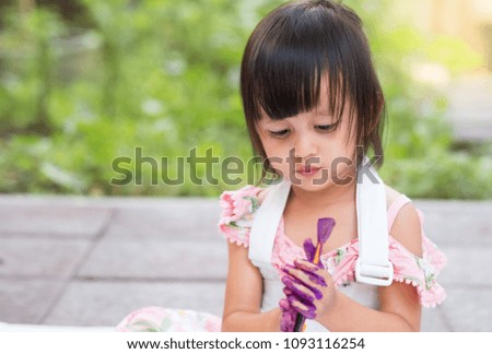 Cute asian little girl is painting water color to her hands outside the house, concept of art education learning activity for preschool kid.