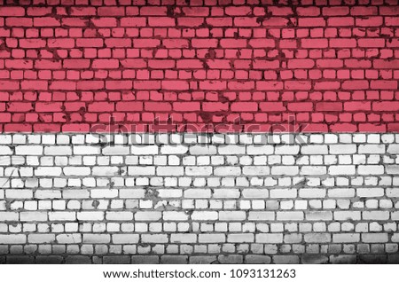 Monaco flag is painted onto an old brick wall