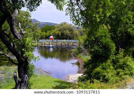 Swimming Hole with Texas Flag framed with Green Trees and Grasses Royalty-Free Stock Photo #1093137815