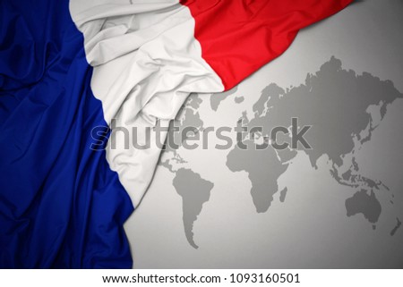 waving colorful national flag of france on a gray world map background.