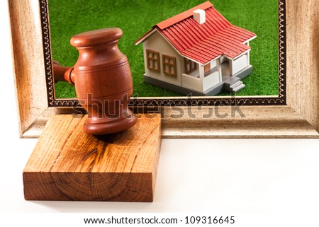 The house on the green grass in the frame and hammer auctioneer