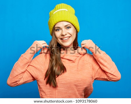 Smiling modern woman wearing pink hoodie with yellow hat. Studio portrait of street style dressed girl.