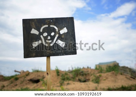 black plate with a white skull on it and bone crossroads warn of danger ahead.