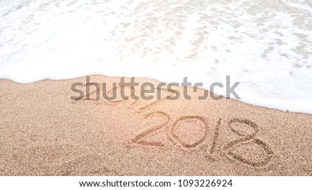 Happy new year 2018 is coming and replace 2017 concept. Number 2018 written on sandy beach with blue sea waves and foam. Holiday, vacation and new year celebration on tropical summer beach. Royalty-Free Stock Photo #1093226924
