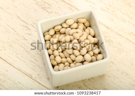 Dry white beans in the bowl over wooden background