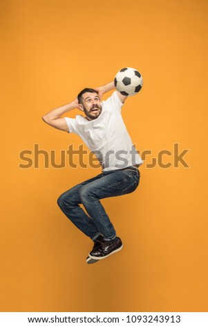 Forward to the victory.The young man as soccer football player jumping and kicking the ball at studio on a yellow background. Football fan and world championship concept. Human emotions concepts