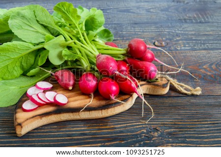Summer harvested red radish. Growing organic vegetables. Large bunch of raw fresh juicy garden radish on dark boards ready to eat. Royalty-Free Stock Photo #1093251725