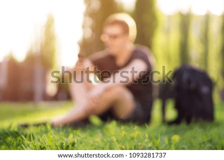 a man sits with a phone on the grass in blur