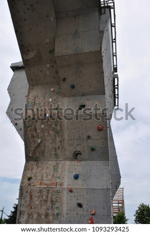 Outdoor construction, wall for training rock climbing, close up detail, gray rainy cloudy sky background