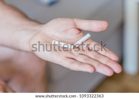 Quit bad habit, health care concept. No smoking. Concept photo of a man quitting smoking by breaking a cigarette. Male hand crushing cigarette. Man trying to quit smoking. Conceptual image