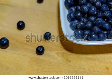 blue berries in on a white dish on a wooden board/background
