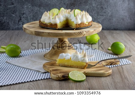 Lime meringue cake with slice cake on confectionery shovel on wooden board