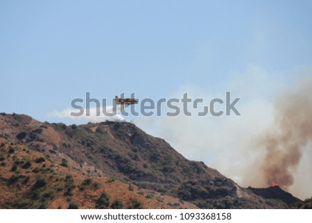 Extinguishing a fire in the mountains using an airplane in a hot summer weather.