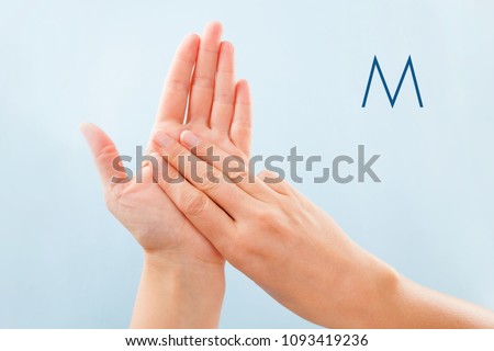 Fingerspelling alphabet. Female hands isolated on blue background showing deaf mute BSL alphabet letter M.
