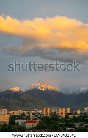 Colourful amazing sunset with clouds over the Almaty city near the mountain.