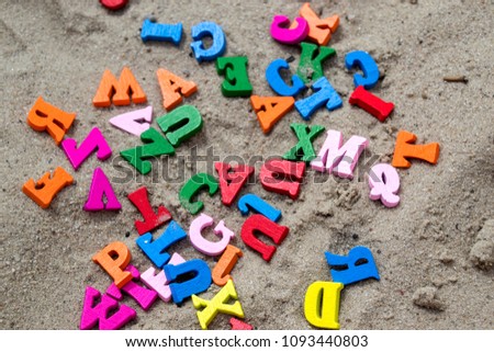 Multicolor wooden letters on a sand close up.