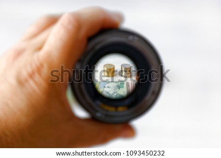 Stack of coins and banknotes viewed through a lens