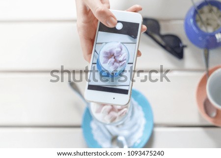 girl takes pictures of fragrant coffee with marshmallow on a wooden table