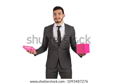 Young man wearing a suit holding an open gift box smiling isolated on a white background
