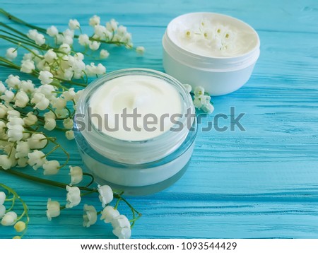 lily of the valley flower cosmetic cream on blue wooden