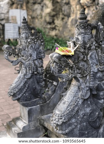 Traditional Balinese statues of the dragon and offerings to the gods in Bali with flowers and aromatic sticks. 
