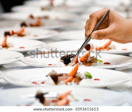 A chef decorates many plates of cake Royalty-Free Stock Photo #1093615613