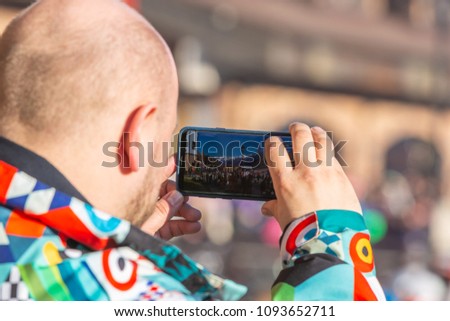 man in a jacket takes pictures of the landscape on the phone