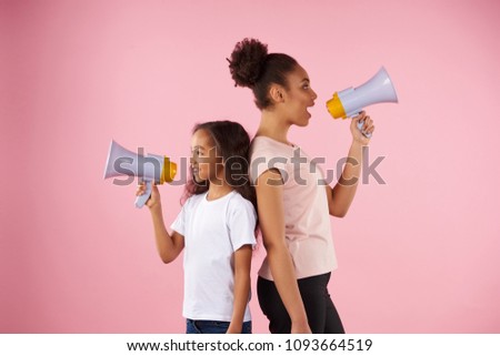 African American woman and little girl are broadcasting in megaphone. Isolated on pink background. Studio portrait.