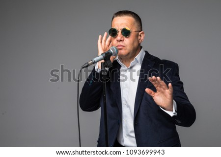 Middle aged man happy and motivated, singing a song with a microphone, presenting an event or having a party, enjoy the moment
