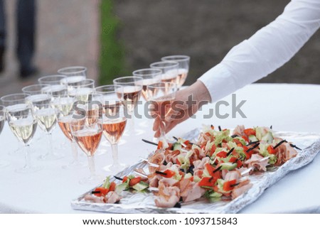 Beautiful row line of different colored alcohol cocktails on a party, martini, vodka,and others on decorated catering bouquet table on open air event, picture with beautiful bokeh