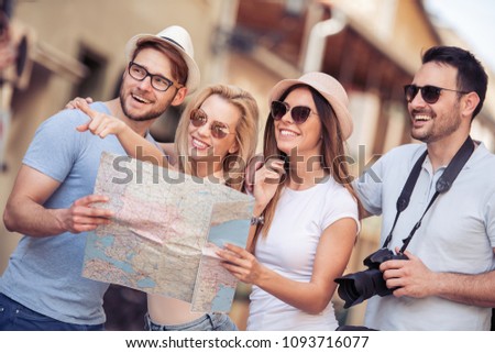 Happy young friends use map to determine direction and point in the way they wish to go.People,friendship,travel,vacation and happiness concept.