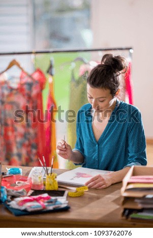 Fashion designer working on a new model in her studio, she designs a new dress