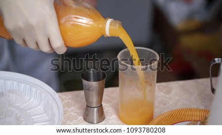Male Hand Holding Orange Soda Bottle Tight And Close Pours Into A Glass Outside. Clip