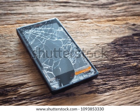 Black smartphone broken glass on old wooden board in the concept of mobile maintenance, accidental damage. In the insurance
