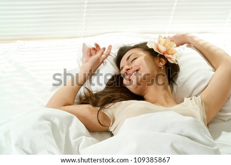 Pretty Caucasian female lying in bed on a light background