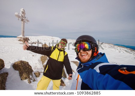 Selfie Guy sportsman goes on normal skiing on ski slope with action camera. Sheregesh background cross