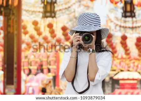 Woman photographer shooting at Chinese temple in Thailand.