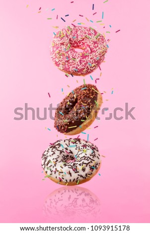 Flying sweet donuts isolated on pink background. Concept of low gravity food in freeze motion effect. High resolution image