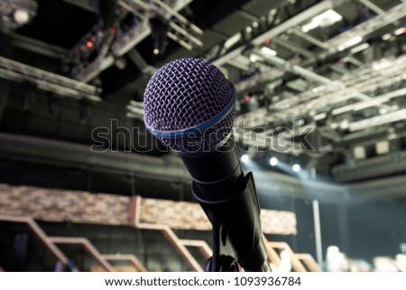 A dynamic microphone on stage. Bright spot light on the background.