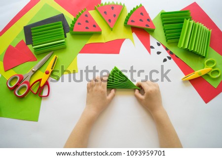 Children's hands make watermelon from paper. Watermelon party preparation.Tropics summer. Master class from the child.