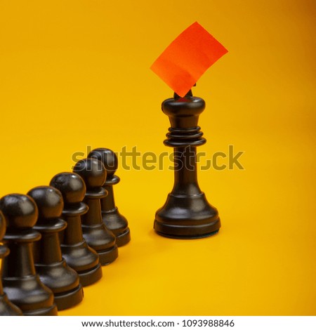 chess pieces on a yellow background and a queen marked with a red mark. 