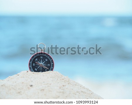 Close up compass  on sand. Sea in soft focus background in Daytime atmosphere.  Search for navigation of life concept.